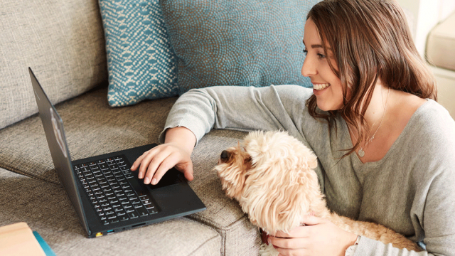 young woman studying online with her dog on her lap