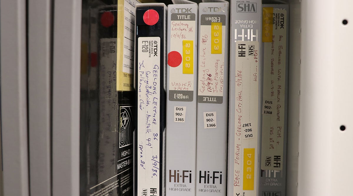 Stack of tapes on a shelf with handwritten labels. Each is a 'Geelong lecture' recording from various dates in 1986.