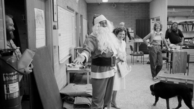 Black and white photo of an office with former Deakin VC Fred Jevons dressed as Santa Claus.