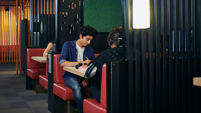 Students sit in a library booth studying