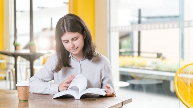Student reads a book at a desk