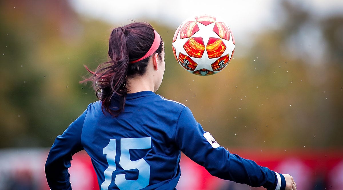 Photo of a female soccer player kicking up a ball