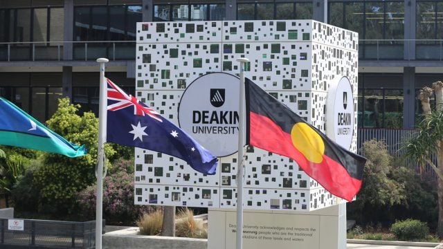The Deakin University cube at Waurn Ponds Campus, located in front of the library. In the foreground of the photo, the Torres Strait Island, Australian and Aboriginal flags fly.