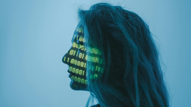 The profile of a woman with computer code lights across her face