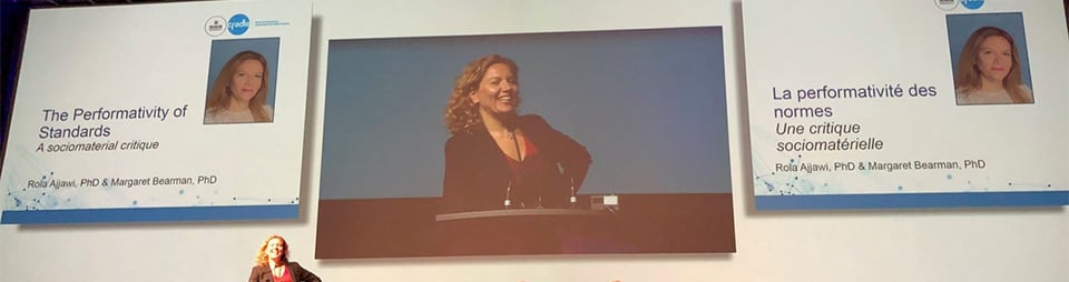 Photograph of Dr Rola Ajjawi presenting at CCME18 in front of a large video screen