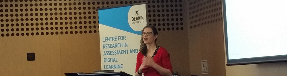 Dr Kate Anderson standing at a lectern, in front of a banner with the Deakin and CRADLE logos