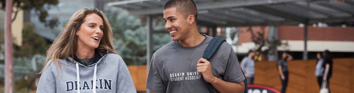 Two students smiling and talking as they walk on campus