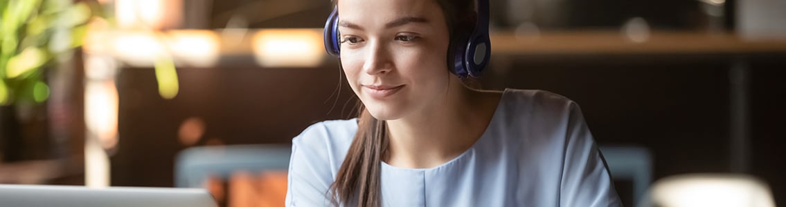 Female wearing headphones and looking at computer
