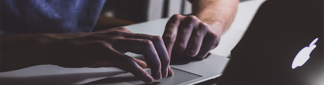 close up of man's hands typing on a laptop