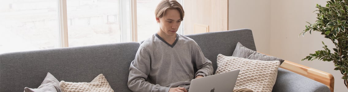 man sitting on couch at home and working on laptop