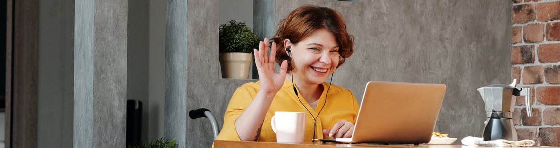 Woman smiling and waving at laptop