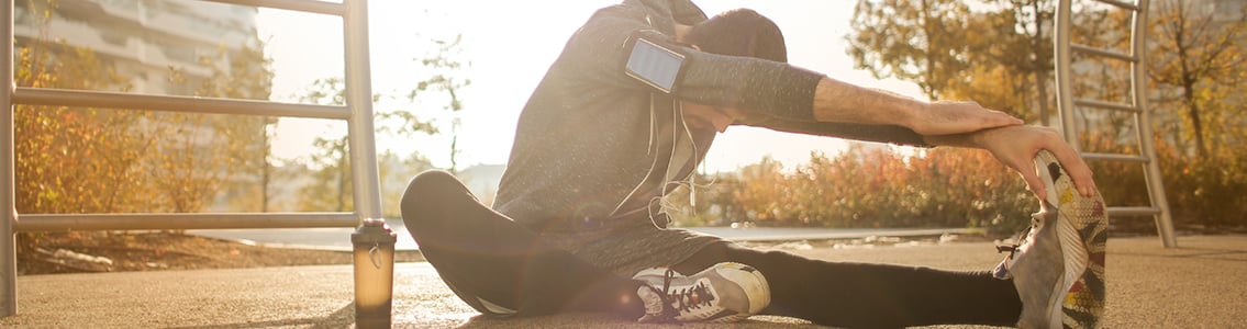 Runner stretching and wearing smartphone