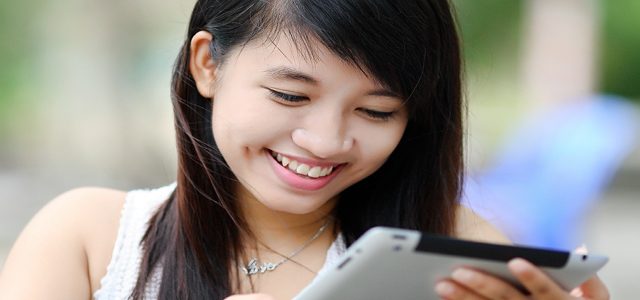 Student smiling as she uses tablet