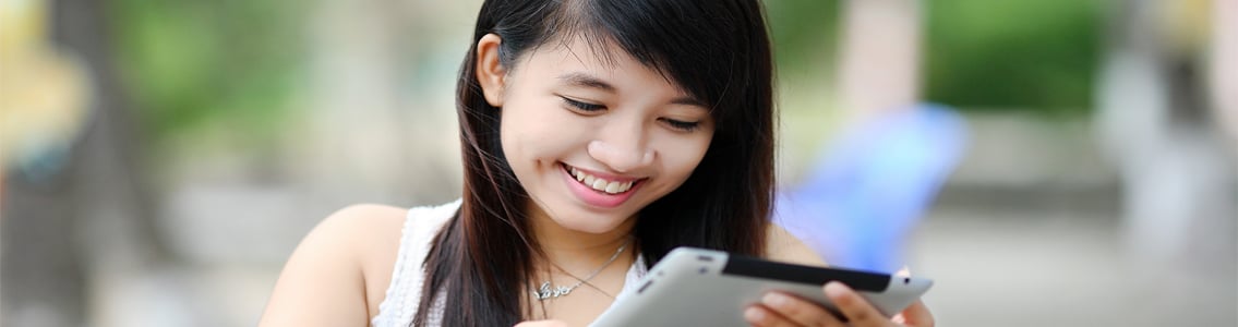Student smiling as she uses tablet