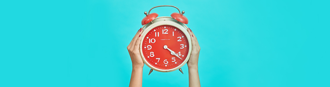 woman's hands holding up clock against cyan background