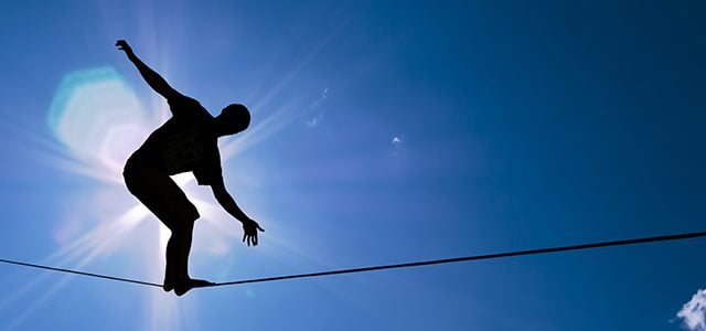 Silhouette of person balancing on tightrope