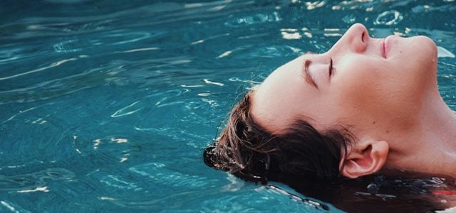 Smiling woman floating in pool with her eyes closed