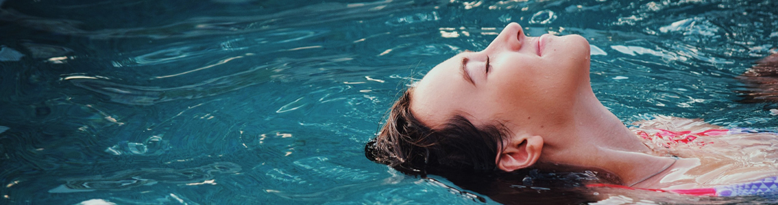 Smiling woman floating in pool with her eyes closed