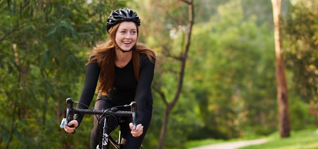 Woman riding her bike through parkland