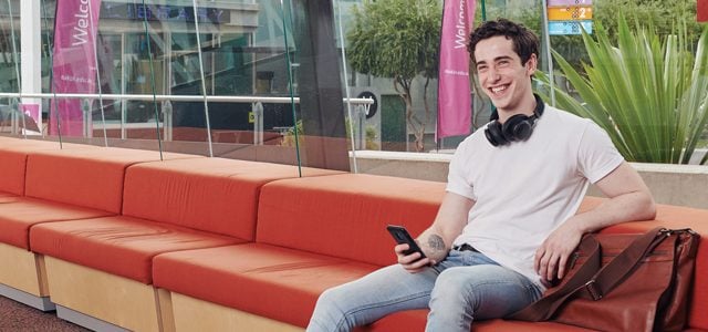 Student smiling as he looks up from phone at Burwood Campus
