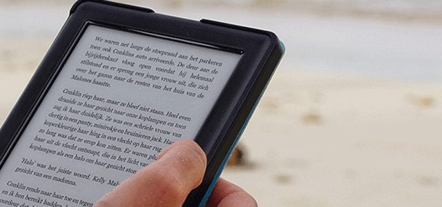 Close-up of person's hand as they read Kindle book on beach