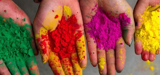 row of open-palm hands holding colourful powder