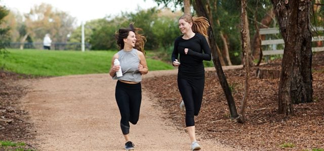 Two students smiling as they jog together outside at Burwood