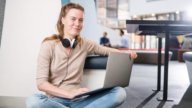 Student smiling as she looks up from laptop on campus