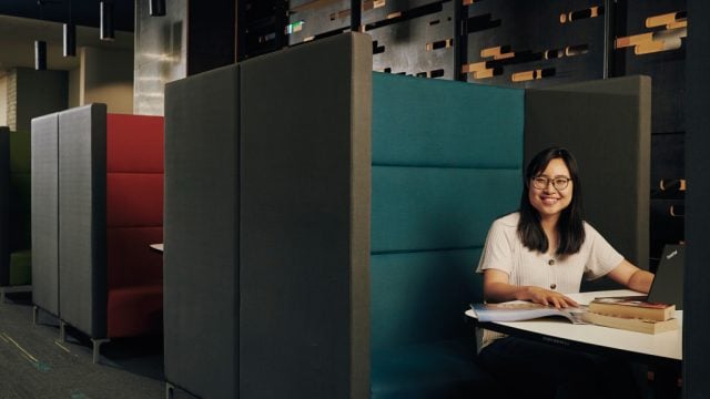 Student smiling as she studies in pod at library