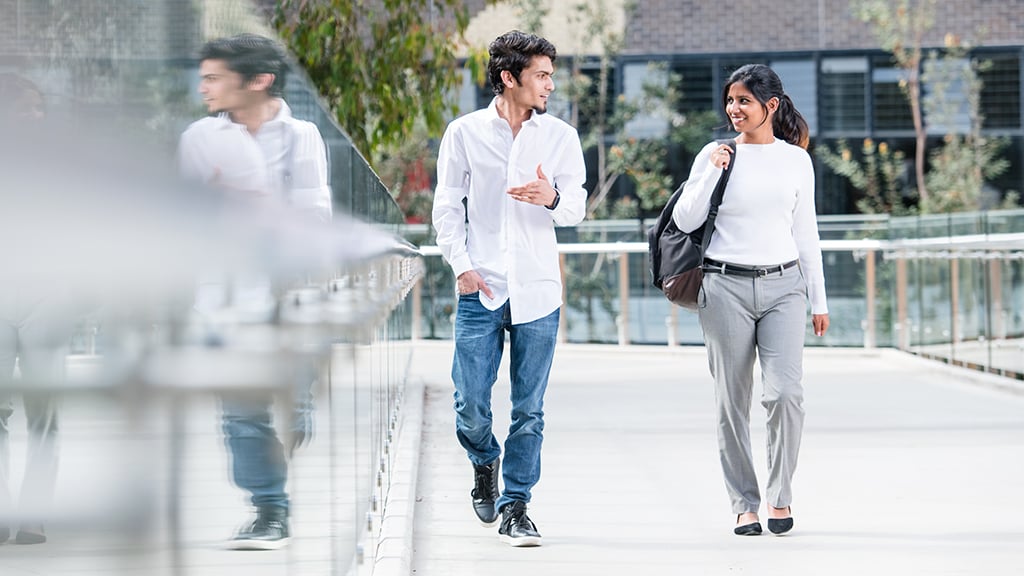 Male and female student walking across campus