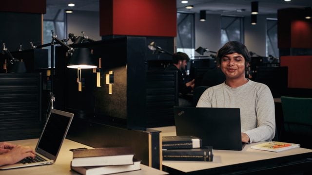 Student smiling as he studies on computer at library