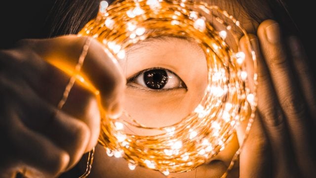 Woman peering through coiled fairy lights