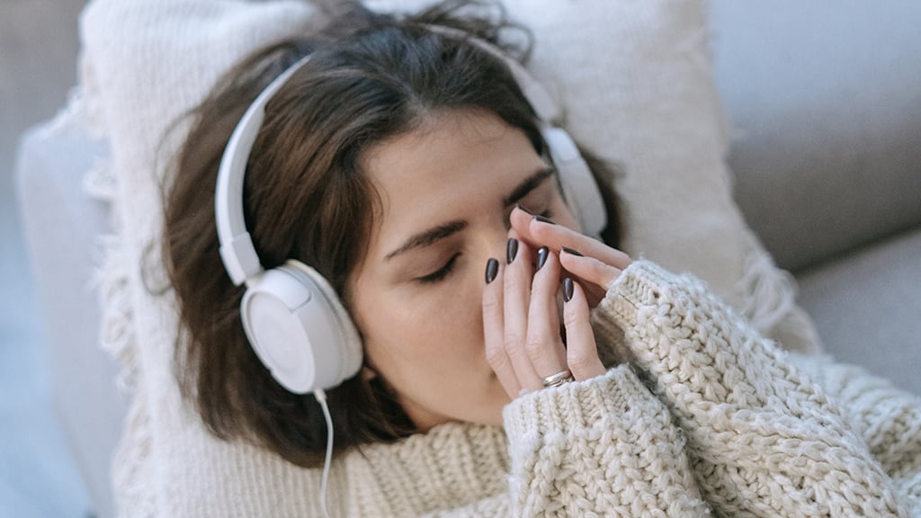 Woman wearing headphones lying down with eyes closed