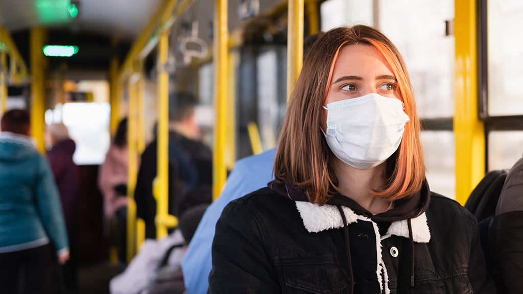Young woman on bus wearing a mask