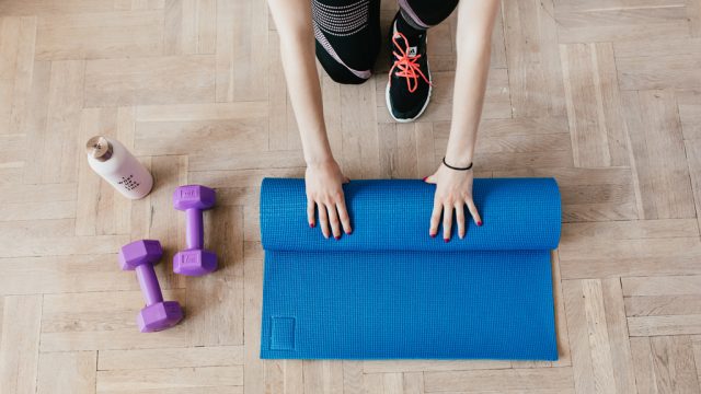 Woman rolling out yoga mat at home