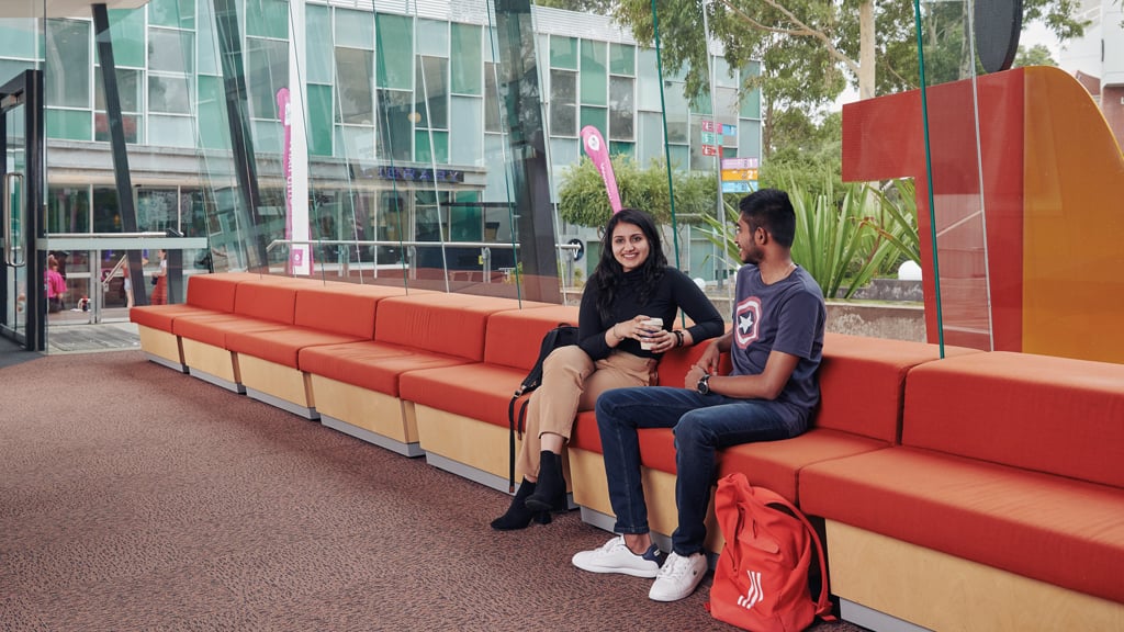 Two students smile as they chat indoors at Burwood Campus