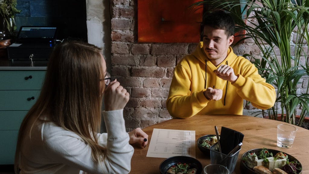 Two people conversing with sign language in a cafe