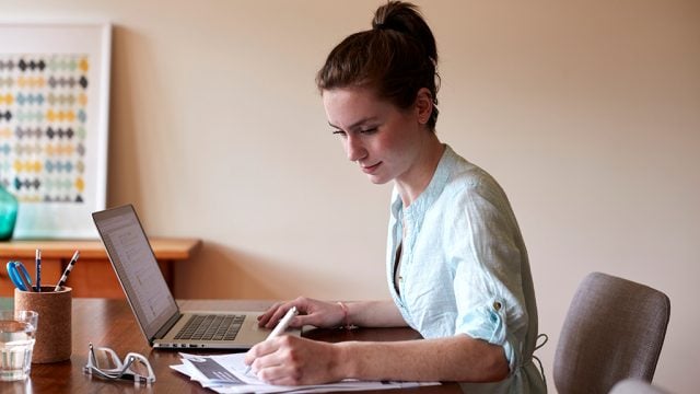 Female student at desk with laptop and notes