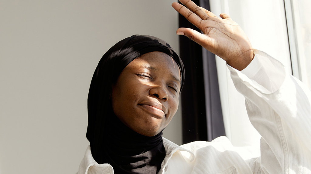 Smiling woman in headscarf shielding face from sun