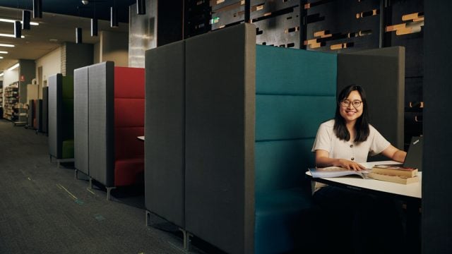 Student smiling as she works from study area in library