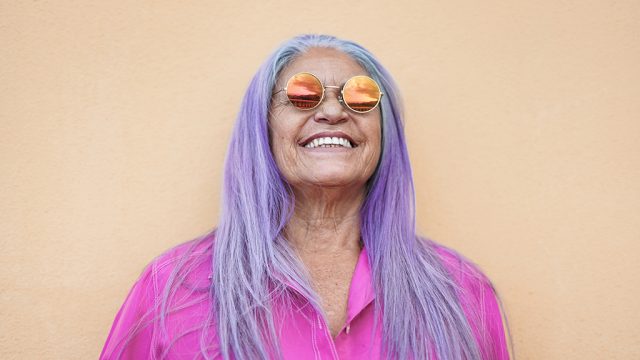Smiling woman with purple hair wearing sunglasses