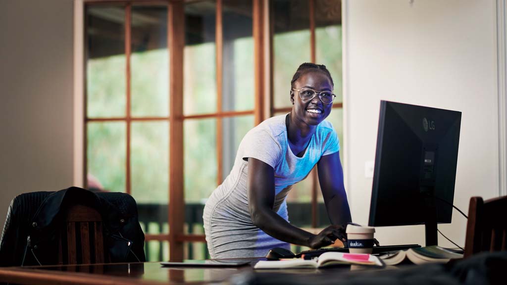 Student smiling as she works on computer at home