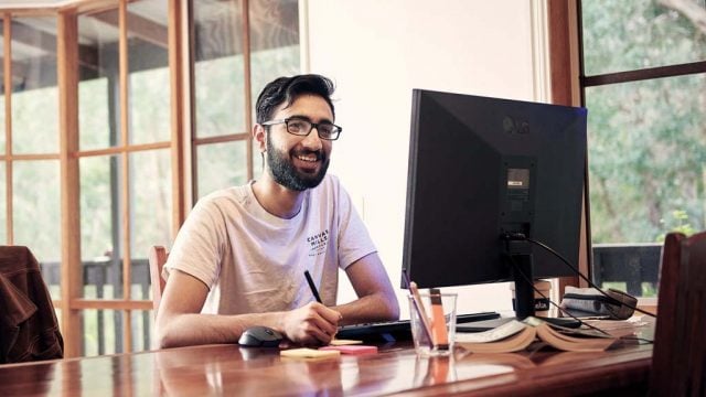 Student smiling as he works on computer at home