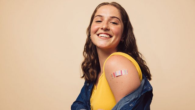 Smiling young woman baring vaccinated arm
