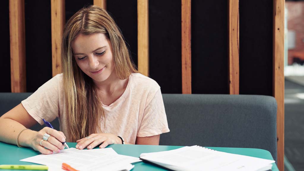 Student smiling as she studies in study hub at Burwood Campus