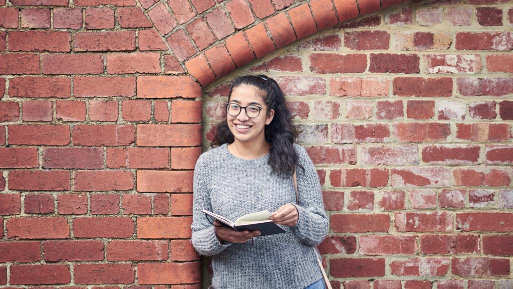 Student holding book outside at Waterfront Campus