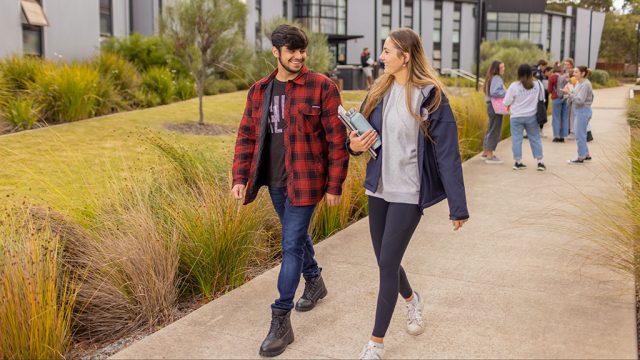 Male and female student chatting as they walk near residences