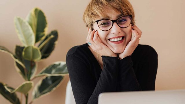 Woman smiling as she looks up from laptop