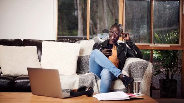 Student smiling as she looks at phone while studying from home