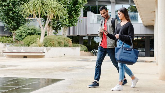 Male and female student walking across Waurn Ponds Campus